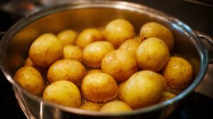 Close-up of whole yellow potatoes boiling in a stainless steel pot