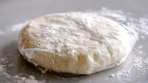 Wrapped pie dough resting on a floured surface